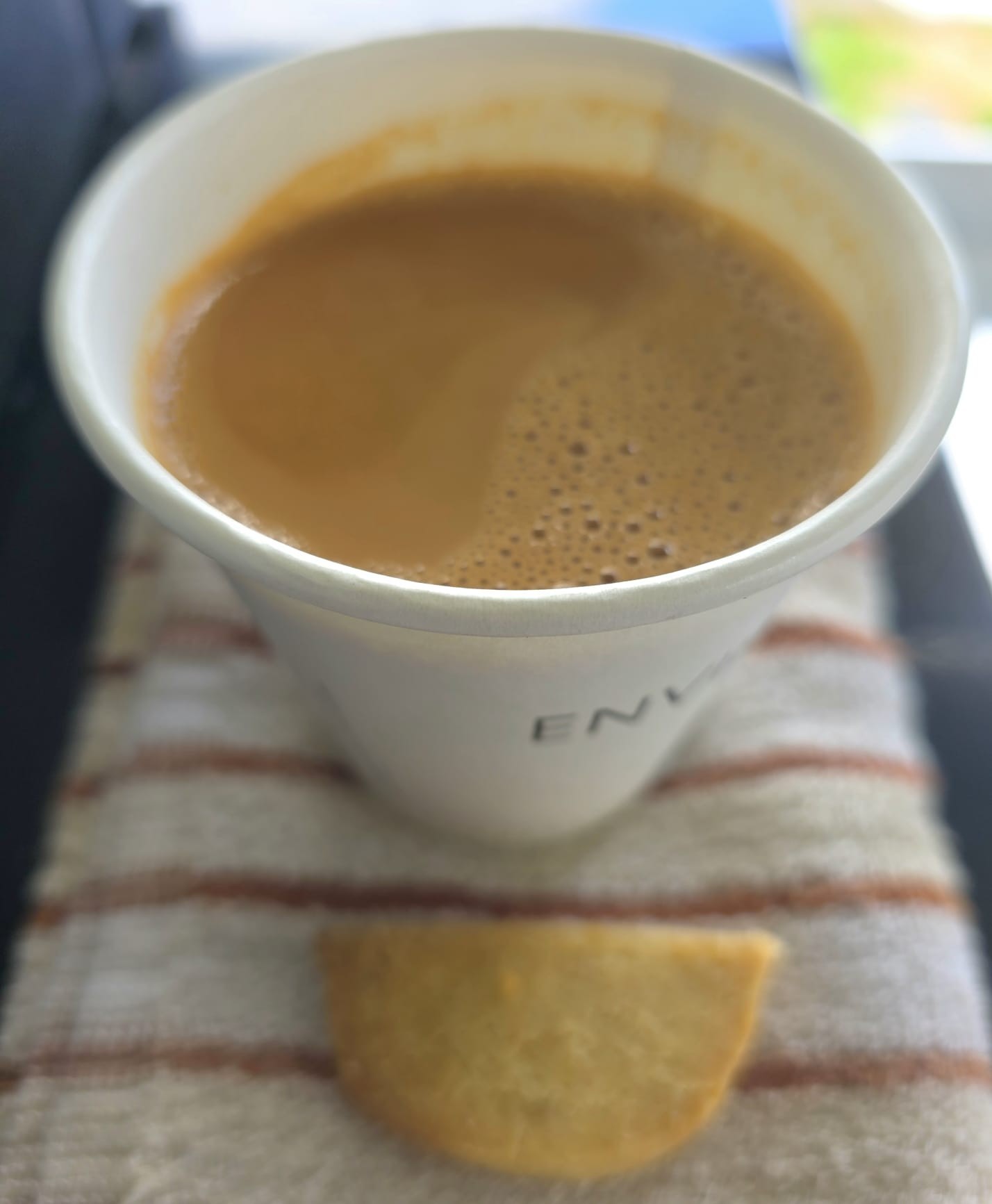 Original close-up photo of coffee in a paper cup with a biscuit